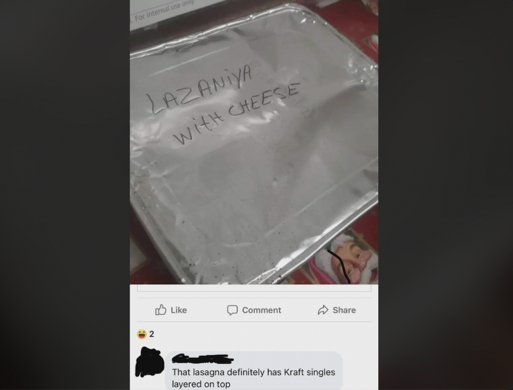 A tin foil-covered dish with "Lazaniya With Cheese" written in marker on top. Below the dish is a screenshot of a Facebook post where a person comments, "That lasagna definitely has Kraft singles layered on top." The reactions show one like and one laugh.