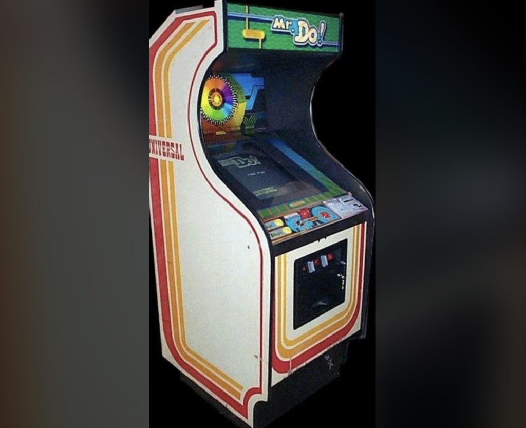 A vintage arcade machine for the game "Mr. Do!" It features a colorful, curved cabinet with red and yellow stripes, a joystick, and several buttons on the control panel. The game's title is prominently displayed at the top.