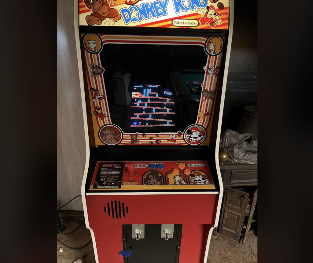 An arcade machine with colorful artwork featuring the classic game "Donkey Kong." The screen displays the game in progress, with Mario climbing ladders and dodging barrels to rescue a damsel in distress. The machine has control buttons and a joystick.