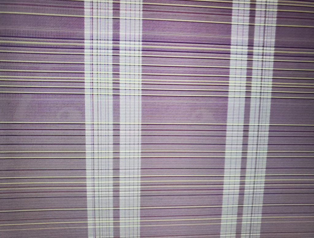 A close-up image of a fabric with a striped pattern in shades of purple, pink, and white. The stripes run both vertically and horizontally, intersecting to create a plaid-like design. The texture of the fabric is slightly visible.