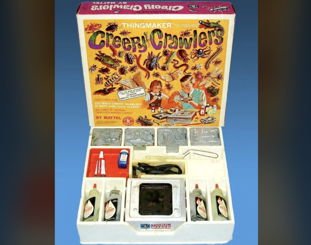 An open box of the vintage "Creepy Crawlers" Thingmaker by Mattel. The set contains various molds, bottles of colored goop, a heating unit, and accessories for creating rubbery bug-like creatures. The box lid features illustrations of children making and playing with the creatures.