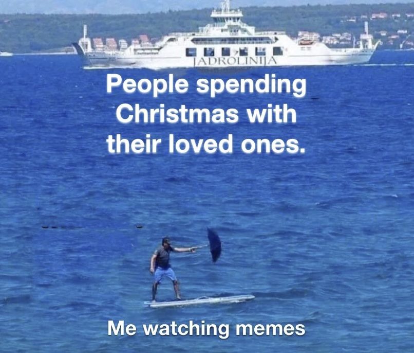 A person stands on a paddleboard in the ocean, holding an umbrella. In the background, there's a ferry. Text on the image reads, "People spending Christmas with their loved ones," and "Me watching memes.