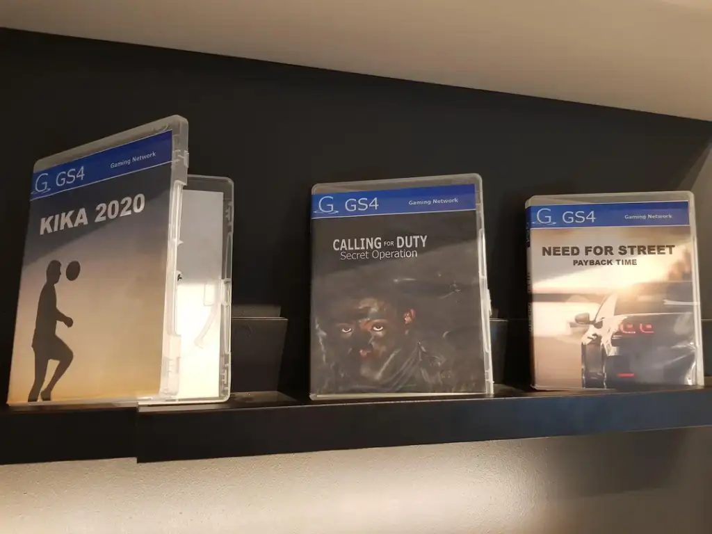 Three video game cases on a shelf: "KIKA 2020" with a silhouetted figure, "CALLING no DUTY: Secret Operation" showing a close-up face, and "NEED FOR STREET: Payback Time" featuring a car tail light and cityscape.