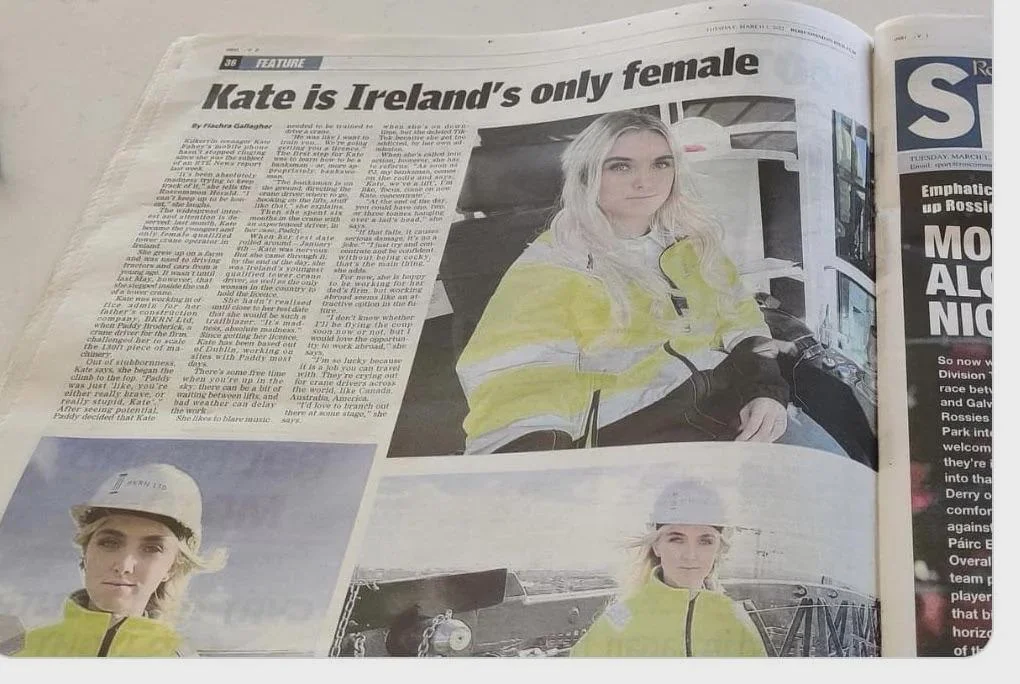 Newspaper article featuring a woman in high-visibility work attire. The headline reads, "Kate is Ireland's only female." Several images of her are shown in work environments, including wearing a hard hat and a safety jacket.