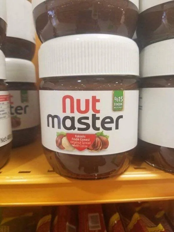 A jar of Nut Master hazelnut spread is placed on a store shelf. The label features images of hazelnuts and cocoa, with the text indicating it's a hazelnut spread with cocoa.