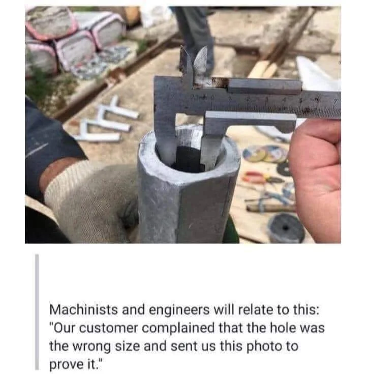 A person measures the inside diameter of a pipe using a caliper. The pipe is in an industrial setting, with tools and equipment visible in the background. A caption below humorously mentions verifying a complaint about the wrong hole size.