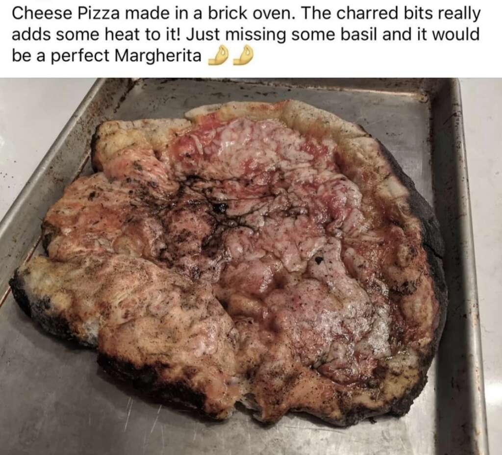 A cheese pizza with charred crust on a baking sheet. The texture appears crispy, with some darkened spots. There's a note above the pizza mentioning it's made in a brick oven, highlighting its charred bits and suggesting adding basil for a perfect Margherita.