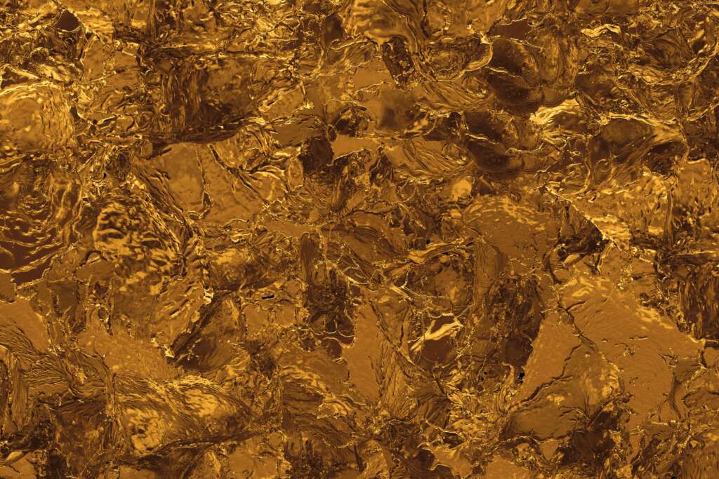 A close-up view of a golden, textured surface resembling crumpled foil or abstract ripples. The surface has a metallic sheen and intricate patterns that catch light, creating a shiny, reflective appearance.