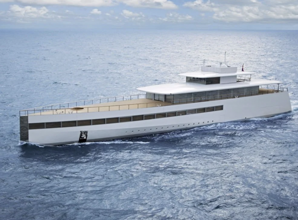 A sleek, modern yacht with clean lines and a minimalist design glides through calm ocean waters under a partly cloudy sky. The vessel has multiple decks and reflective windows, surrounded by a blue sea.