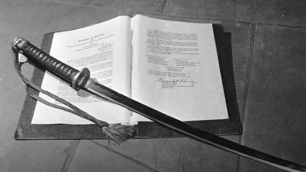 A katana lies across an opened document on a stone surface. The document has typed text and several signatures on it. The scene is captured in black and white.