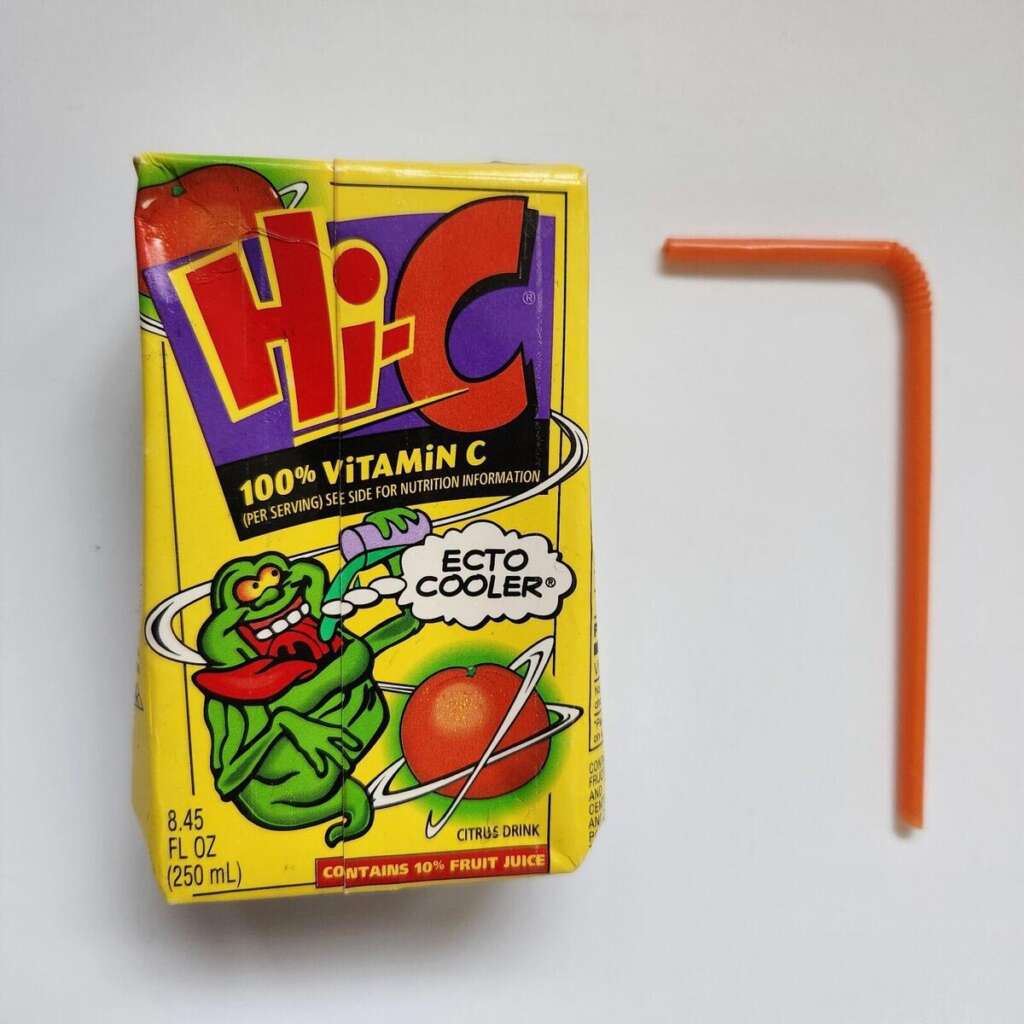 A Hi-C juice box with a colorful design featuring a ghost holding a fruit. The flavor is "Ecto Cooler," with 100% vitamin C. An orange straw is placed next to the juice box on a white background.