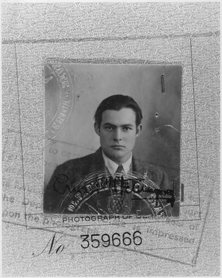 Black and white passport photo of a man in a suit and tie, centered within a patterned border. The image includes visible text and a seal. The photo has a vintage appearance.