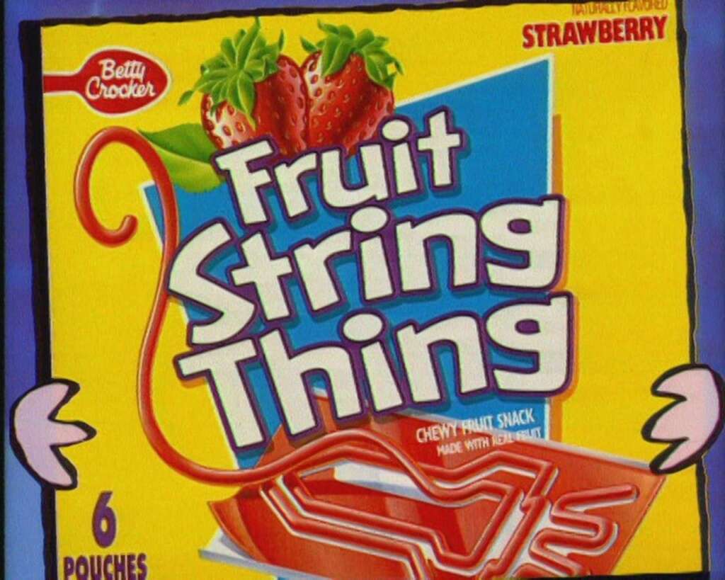 A colorful box of Betty Crocker Fruit String Thing featuring strawberries and colorful graphics. The text highlights "Chewy Fruit Snack" and "Strawberry." The box contains six pouches.