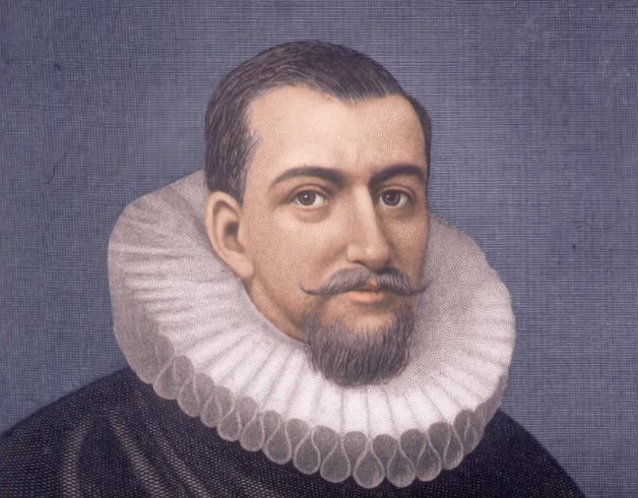 A portrait of a man with a short beard and mustache, wearing a detailed white ruffled collar and a dark outfit. He has short hair and is set against a soft blue-gray background. His expression is calm and serious.