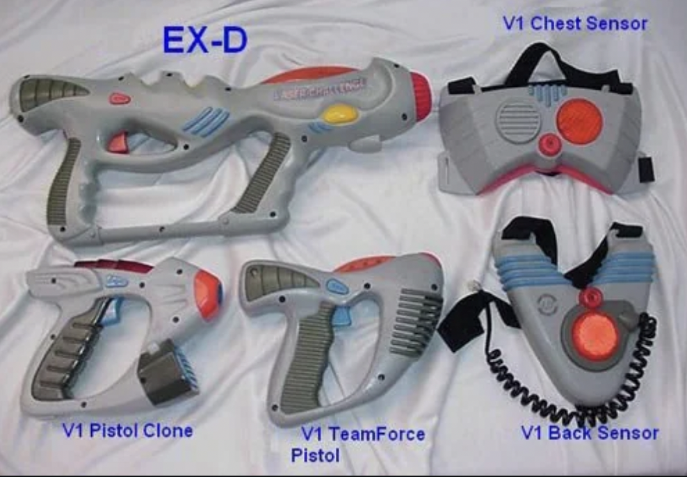 A collection of gray and red laser tag gear labeled "EX-D." Includes a V1 chest and back sensor, V1 Pistol Clone, and V1 TeamForce Pistol. They are placed on a white surface.