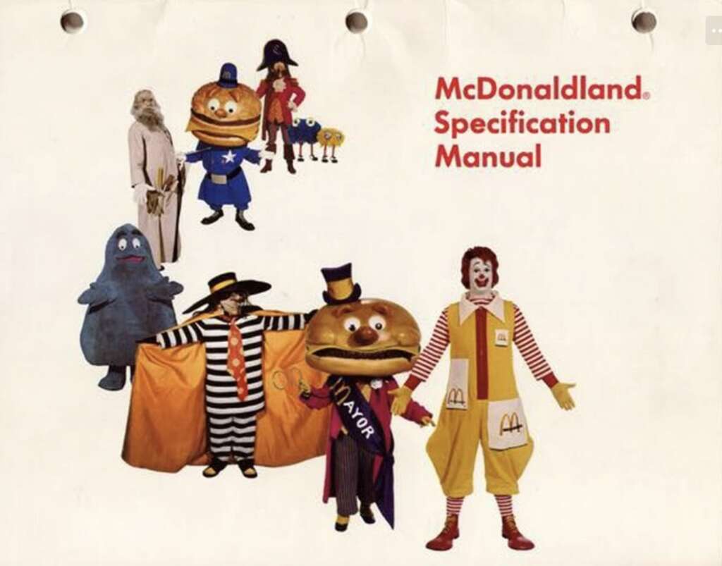 Illustration from the McDonaldland Specification Manual featuring various characters, including a clown, a large burger figure with "Mayor" sash, and other colorful, costumed figures against a white background.