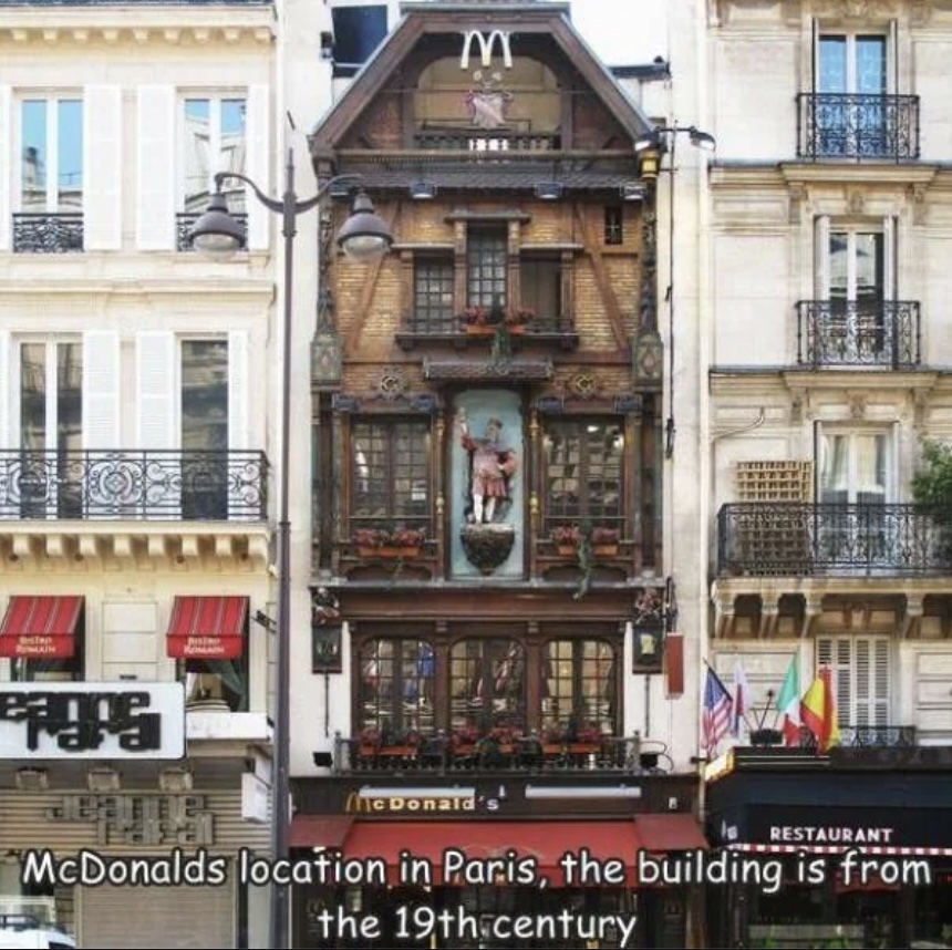 A McDonald's in Paris occupies a narrow, ornate 19th-century building with decorative elements. It's situated between two other classic Parisian facades. A sign at the bottom reads "McDonald's.