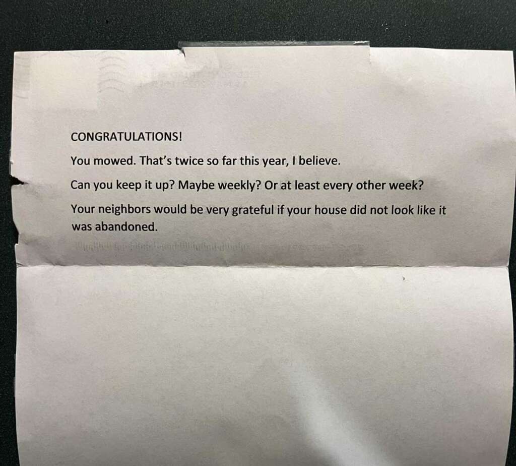 A typed note on white paper reads: "Congratulations! You mowed. That's twice so far this year, I believe. Can you keep it up? Maybe weekly? Or at least every other week? Your neighbors would be very grateful if your house did not look like it was abandoned.