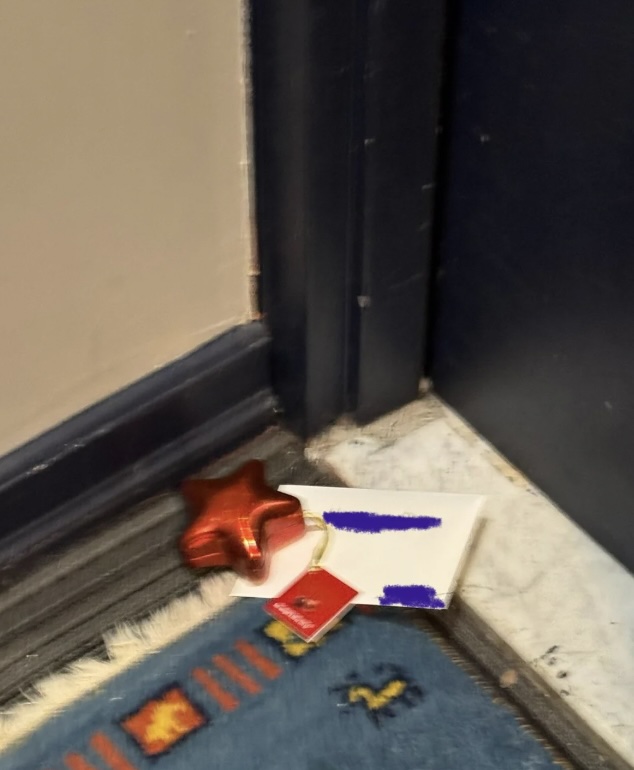 A star-shaped balloon and two unopened white envelopes are placed on a doormat near a blue door.