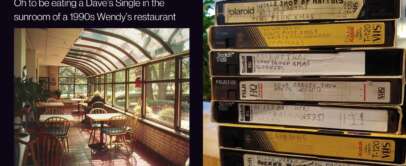 A 1990s Wendy's sunroom with wooden tables and chairs has sunlight streaming in through large windows. Next to it, a stack of labeled VHS tapes is arranged vertically, featuring various TV shows and movies.