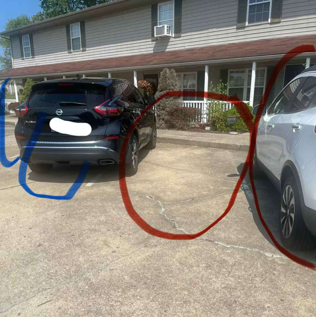 Two cars are parked in a driveway in front of a beige building with a red-brown roof. The car on the left is black, and the one on the right is white. Colored lines are drawn over parts of the image.