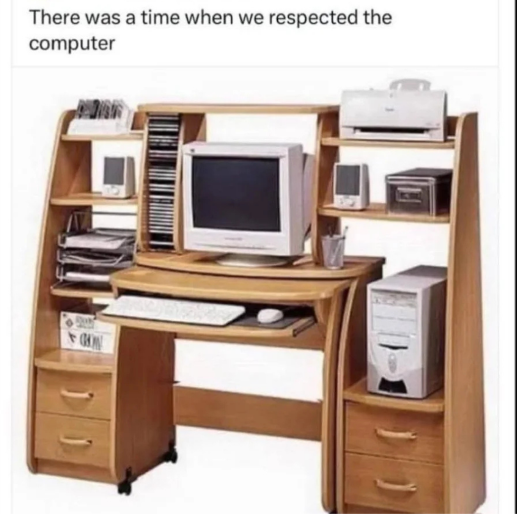 A vintage computer setup on a classic wooden desk with a CRT monitor, tower, keyboard, mouse, and a printer. The desk has shelves for CDs and accessories. Text above reads, "There was a time when we respected the computer.