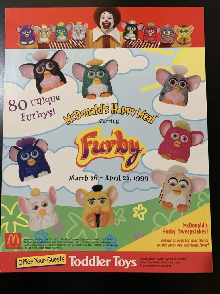 A McDonald's advertisement showcases the 1999 Happy Meal featuring 80 unique Furby toys. The poster includes images of various Furbys with different colors and designs. The promotion runs from March 26 to April 22, 1999.