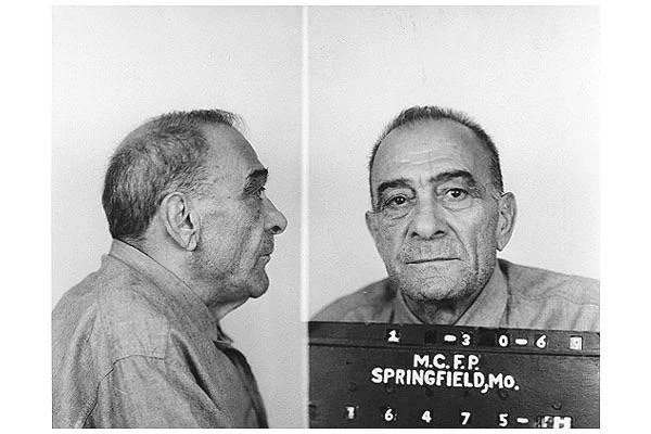 An older man with short hair is shown in a black and white mugshot. The image includes a side profile and a front-facing view. He is wearing a collared shirt, and the board reads "M.C.F.P SPRINGFIELD, MO" with identification numbers.