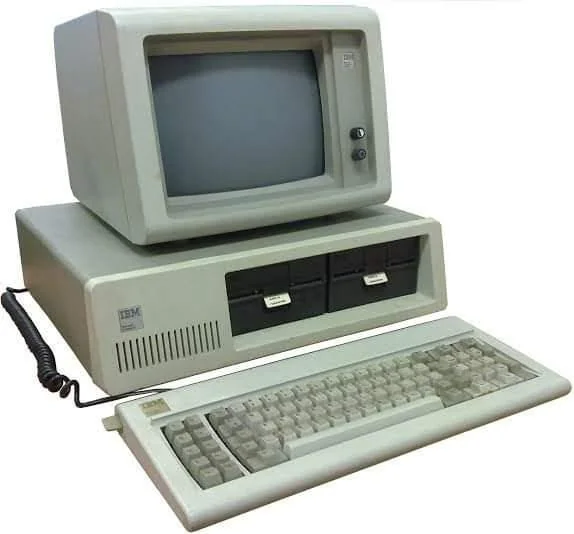 An early personal computer with a monochrome CRT monitor, dual floppy disk drives, and a full-size keyboard. The computer is beige and has an IBM logo on the front of the tower and monitor.