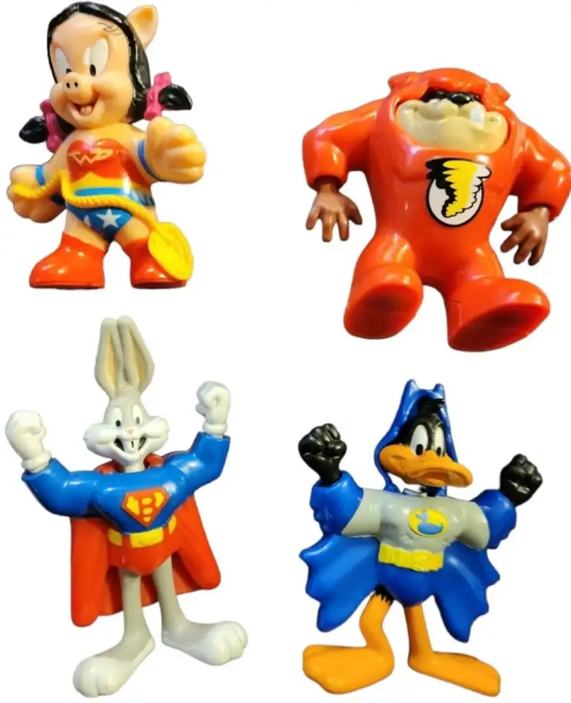 Four cartoon character figurines dressed as superheroes: A character in a red and yellow suit with a lasso, a character in an orange suit with a beak on the chest, another in a blue and red outfit, and one in a blue cape with a duck bill.