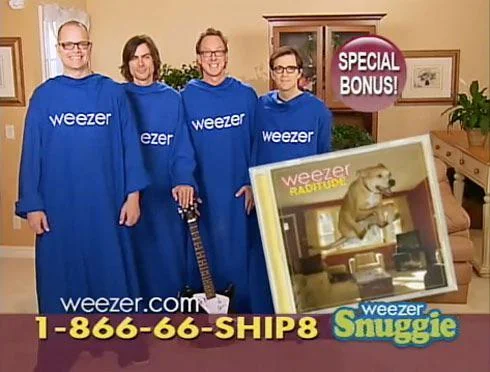 Four people in blue Weezer Snuggies stand in a living room. Text reads "SPECIAL BONUS" and shows a Weezer album cover with a dog. A guitar rests against the sofa. Contact details are at the bottom.