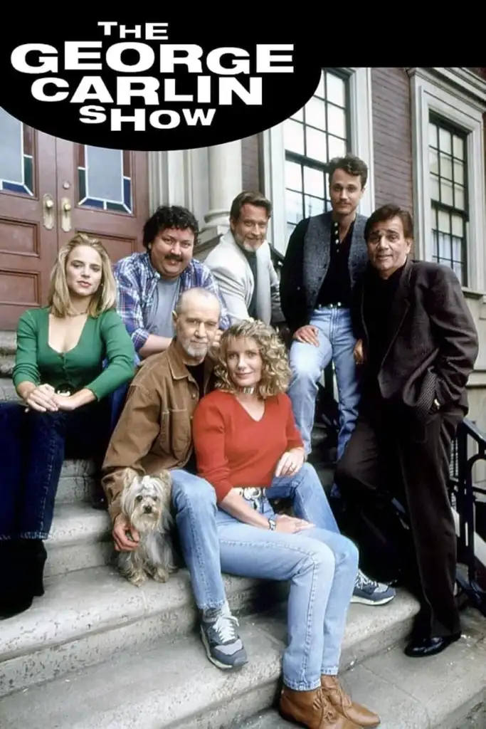 The cast of "The George Carlin Show" sits and stands on outdoor steps. Seven people, including men and women, with one holding a small dog. The show's title appears at the top in bold letters.