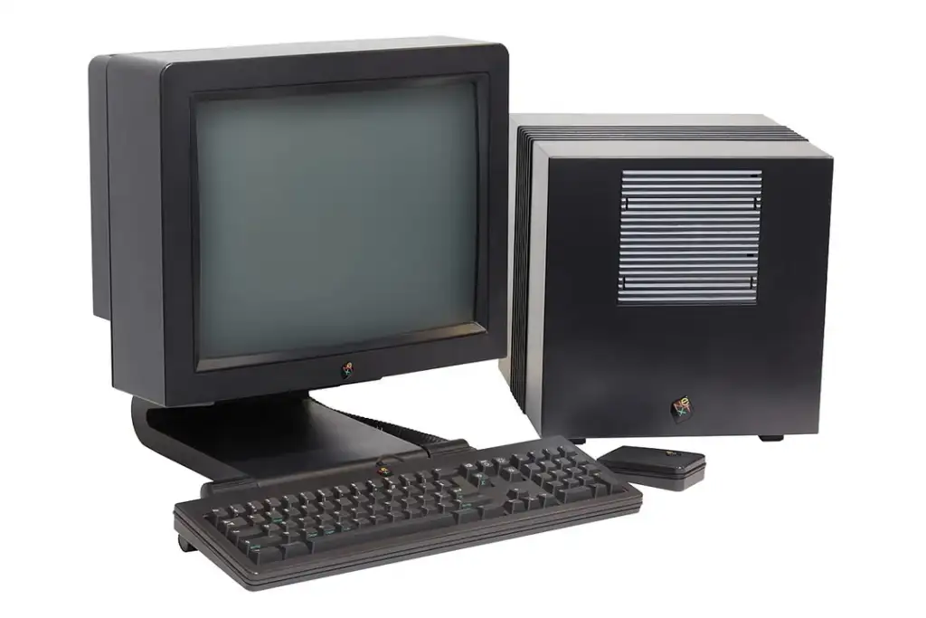 A vintage black computer setup featuring a CRT monitor, a square, vented tower case, a keyboard, and a rectangular mouse. The design and components suggest a retro style from the late 20th century.