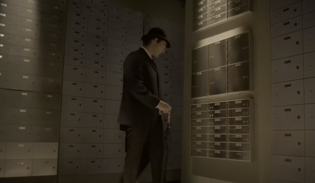 A person in a suit and hat stands in a dimly lit room filled with safety deposit boxes. They are holding a gun and are looking at an open box on the wall. The atmosphere is tense and secretive.