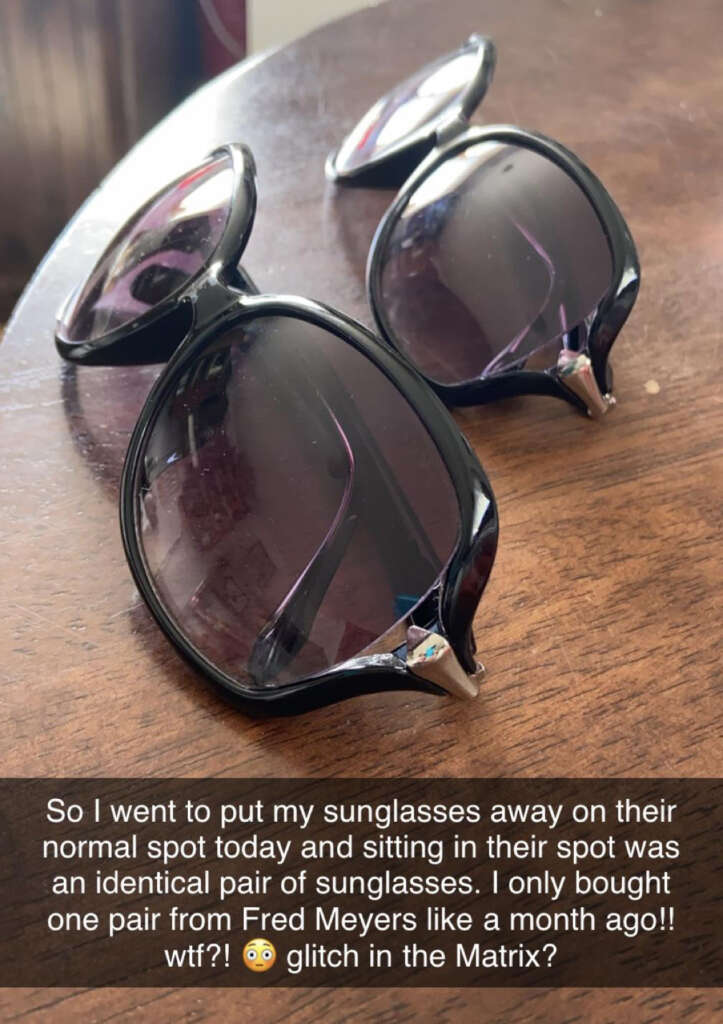 Two pairs of identical black sunglasses with tinted lenses are placed on a wooden surface. A caption below expresses surprise at finding the second pair, questioning if it’s a "glitch in the Matrix.