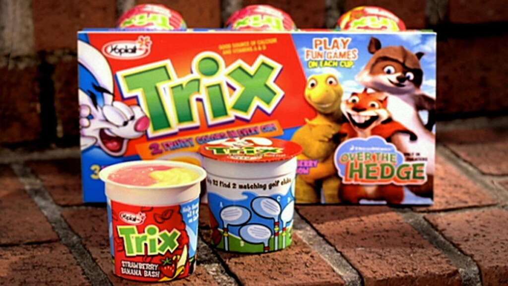 The image shows Yoplait Trix yogurt packages on a brick surface. The packaging features colorful designs with cartoon characters. There is also a mention of "Over the Hedge" on the box.