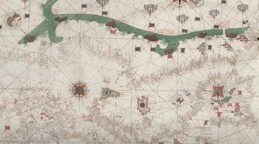 Antique nautical map with intricate compass roses, rhumb lines, and detailed coastlines. The map features a large green landmass at the top and is decorated with various symbols and illustrations.