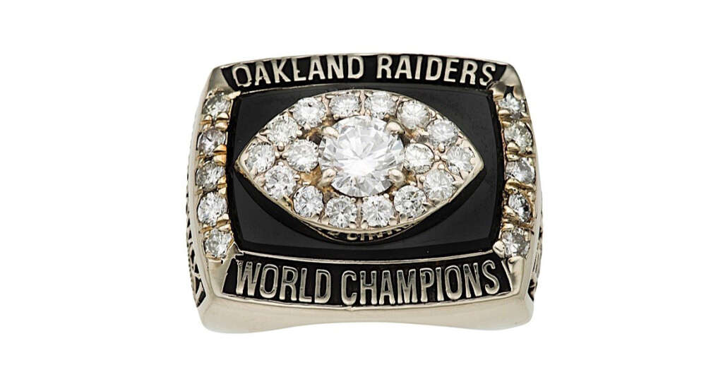 Championship ring featuring the text "Oakland Raiders" on top, "World Champions" on the bottom, and a diamond-encrusted football shape in the center.