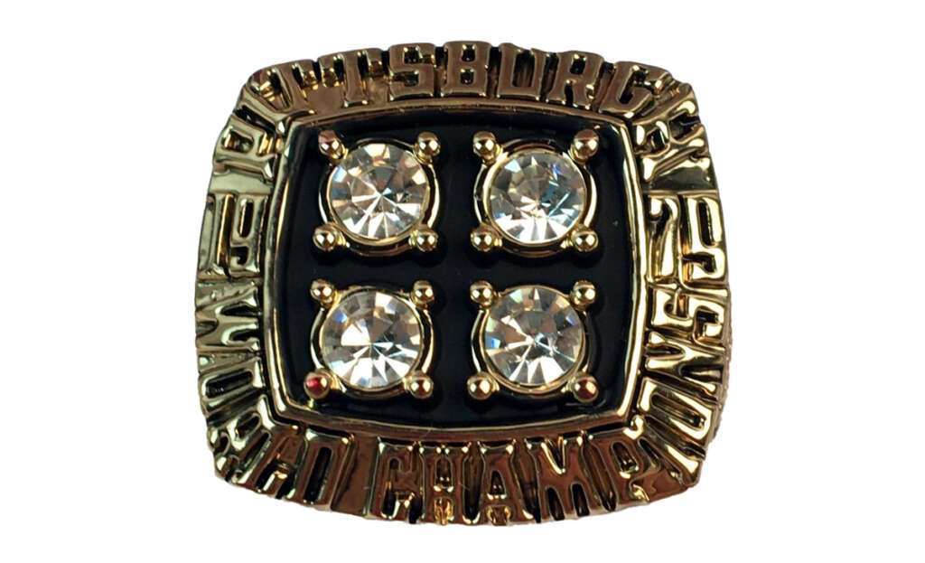 A square championship ring with four large clear stones in the center. The gold band has the engraved text "Pittsburgh World Champions" surrounding the stones.