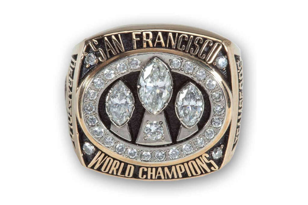 A gold ring with "San Francisco World Champions" engraved. It features three large marquise-cut diamonds surrounded by smaller round diamonds in an oval pattern on the top.