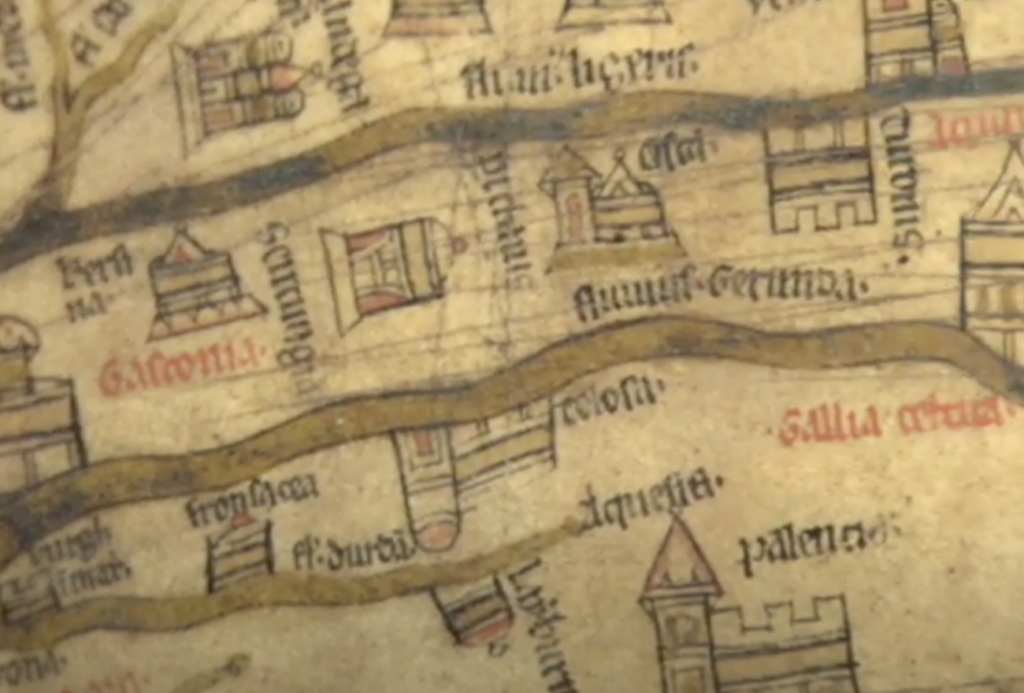 A close-up of a medieval map with hand-drawn buildings, roads, and Latin text. The parchment shows a river with regions and cities labeled in ornate script, alongside illustrations of fortresses and towers. The colors are muted, with faded earth tones.