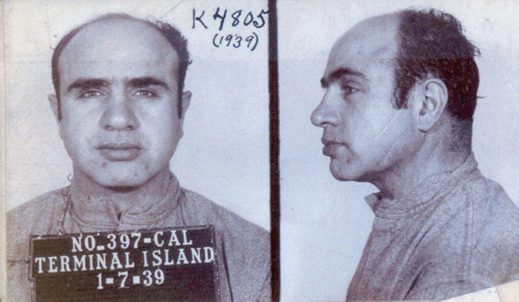 A two-part mugshot of from 1939 showing Al Capone with a receding hairline. The left image is a front view, the right a side profile. He's wearing a plain shirt. The sign reads "No. 397-CAL Terminal Island 1-7-39". Handwritten text "K4805 (1939)" appears at the top.