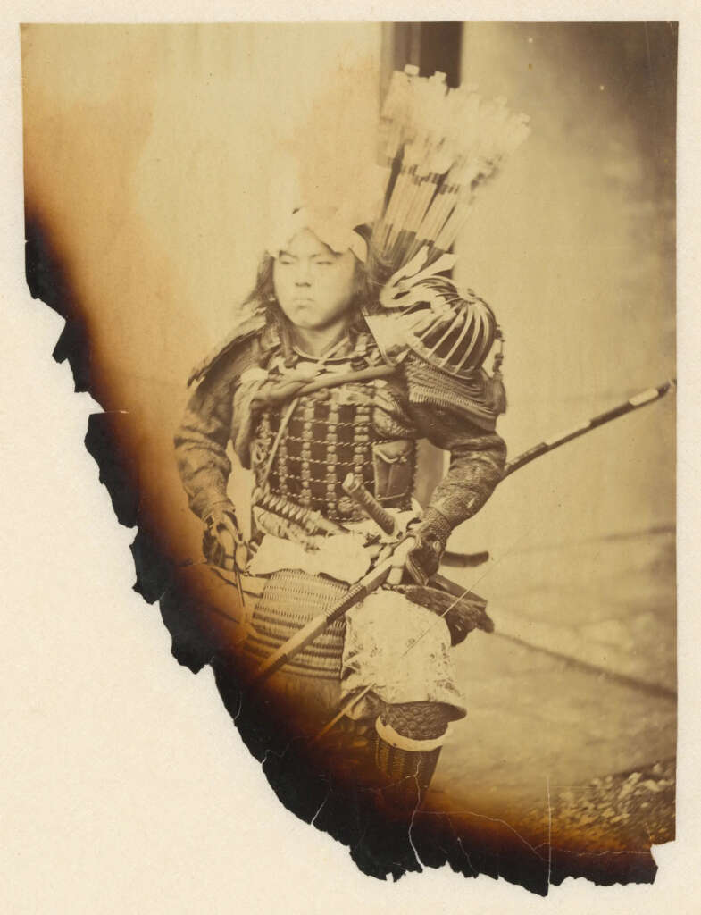 A historical photograph of a samurai in traditional armor, carrying a bow and a quiver of arrows on his back. The image shows signs of aging with a burnt edge effect on the left side. The samurai gazes intently forward.