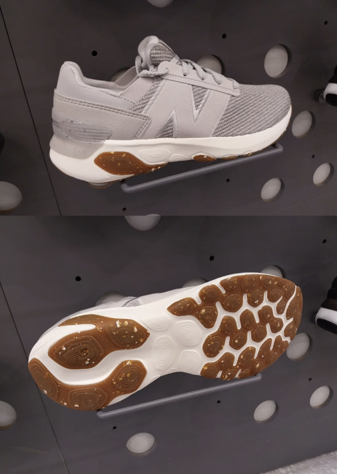 Gray athletic sneakers displayed on a wall, featuring a knit upper with a large "N" logo. The sole is white with a brown, patterned outsole for traction. The upper image shows the side view, and the lower image shows the sole with a honeycomb design.