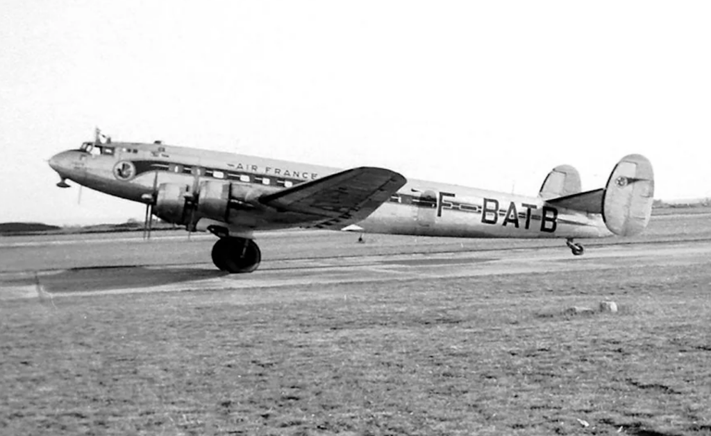 A vintage Air France airplane is parked on a runway. The aircraft has a four-engine propeller design with visible landing gear and identifiable registration markings on the fuselage and tail. The scene is in black and white.