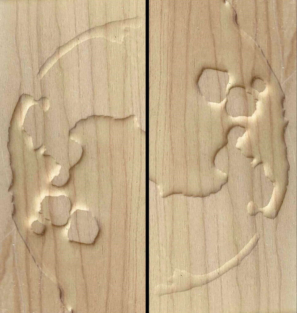 Wooden surface with a carved yin and yang symbol split between two panels. The left panel features the yin side with recessed areas, and the right panel displays the yang side. Both panels have visible wood grain.