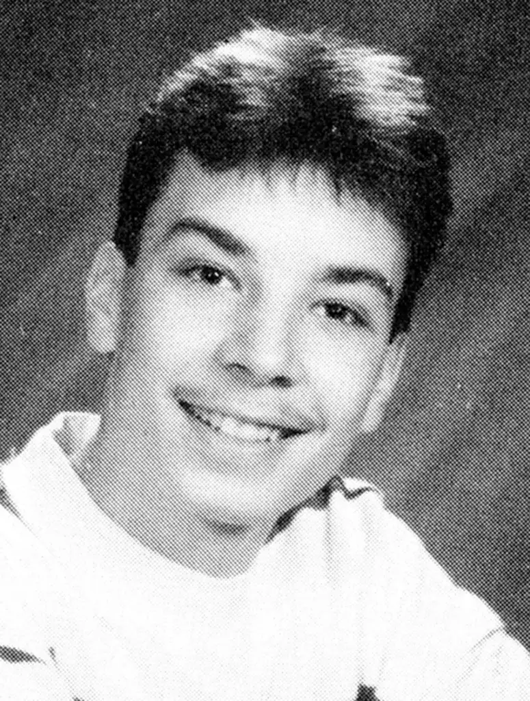 A young person smiling, wearing a light-colored shirt. The portrait has a textured, grayscale effect, typical of a yearbook photo, with the individual looking directly at the camera.