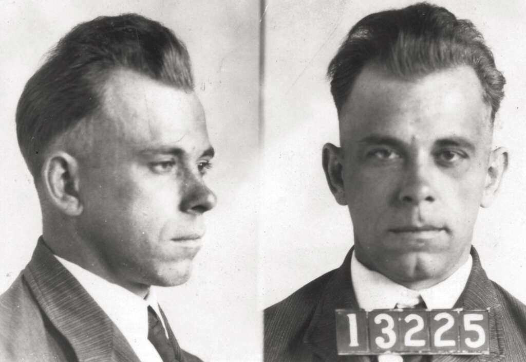 A black and white mugshot featuring two views of a man wearing a suit and tie. The left side shows his profile, and the right side displays a frontal view with a placard bearing the number 13225.