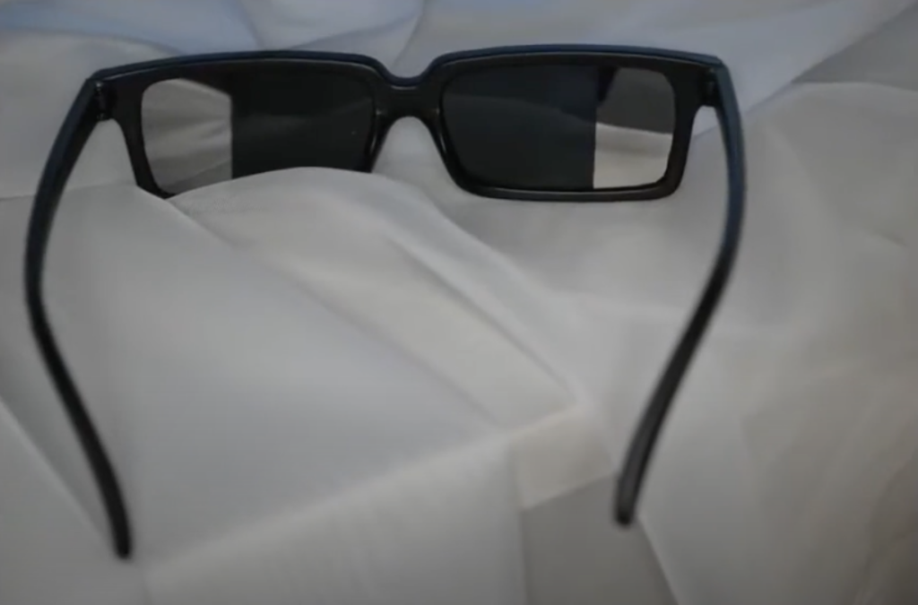 Black rectangular sunglasses resting on a soft, white fabric background.