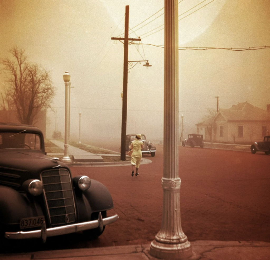 A vintage scene features a person in a light-colored coat running on a foggy street with classic cars parked nearby. A tall streetlamp stands in the foreground, and bare trees are visible against the misty background.